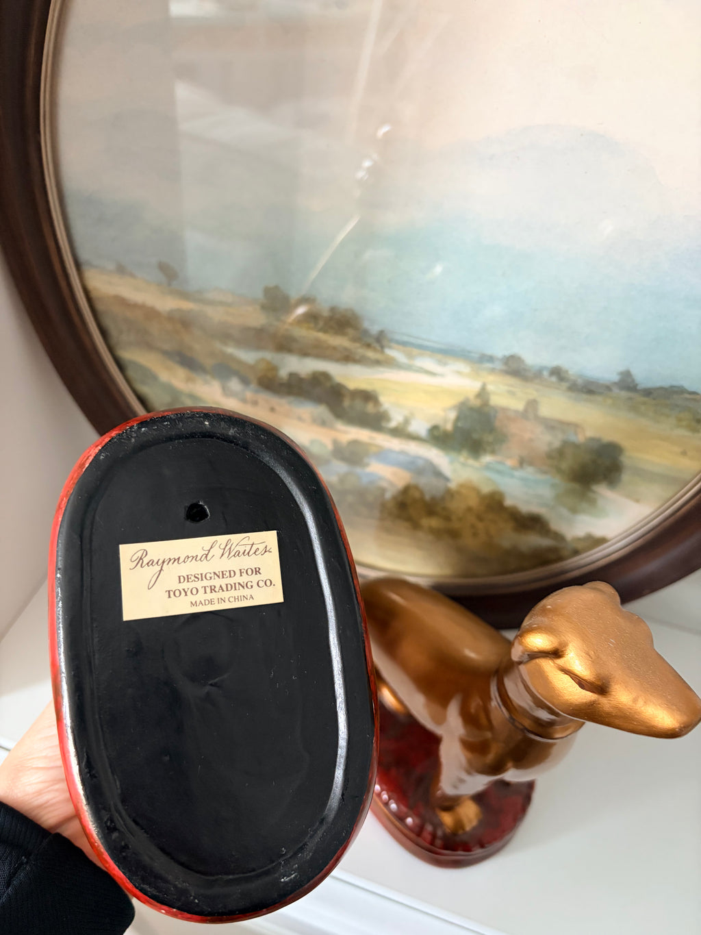 Gold whippet pair viewed from the side on their red cushion bases