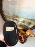 Gold whippet pair viewed from the side on their red cushion bases