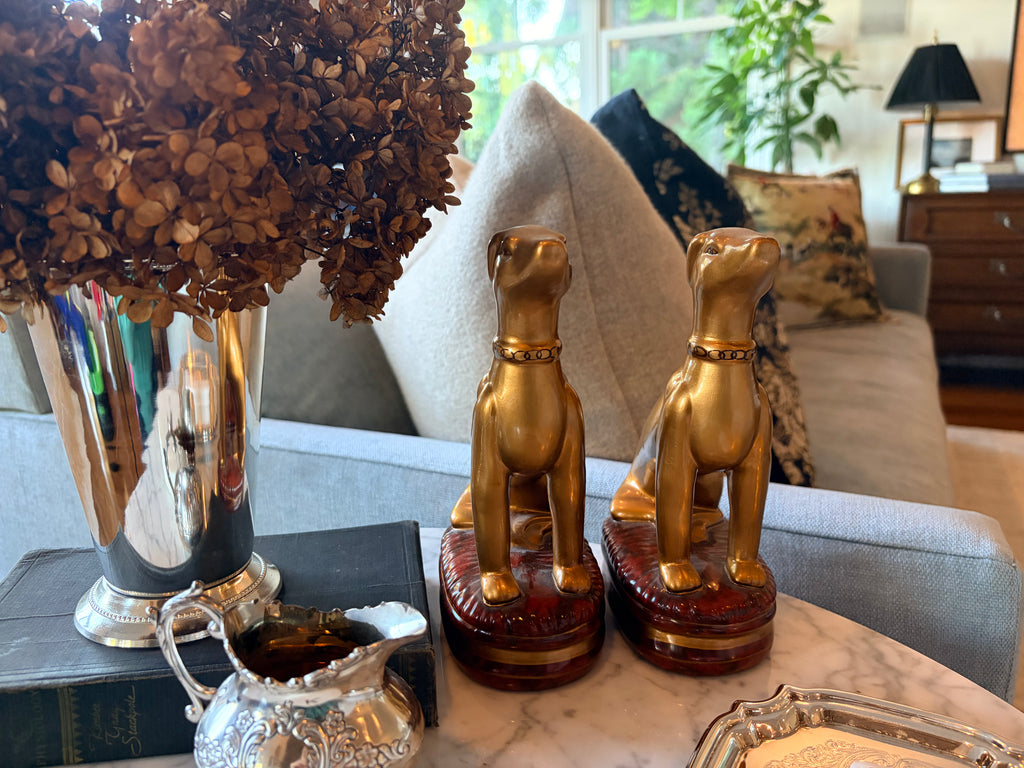 Pair of Raymond Waites gold whippet figurines styled on a bookshelf in a classic English library look