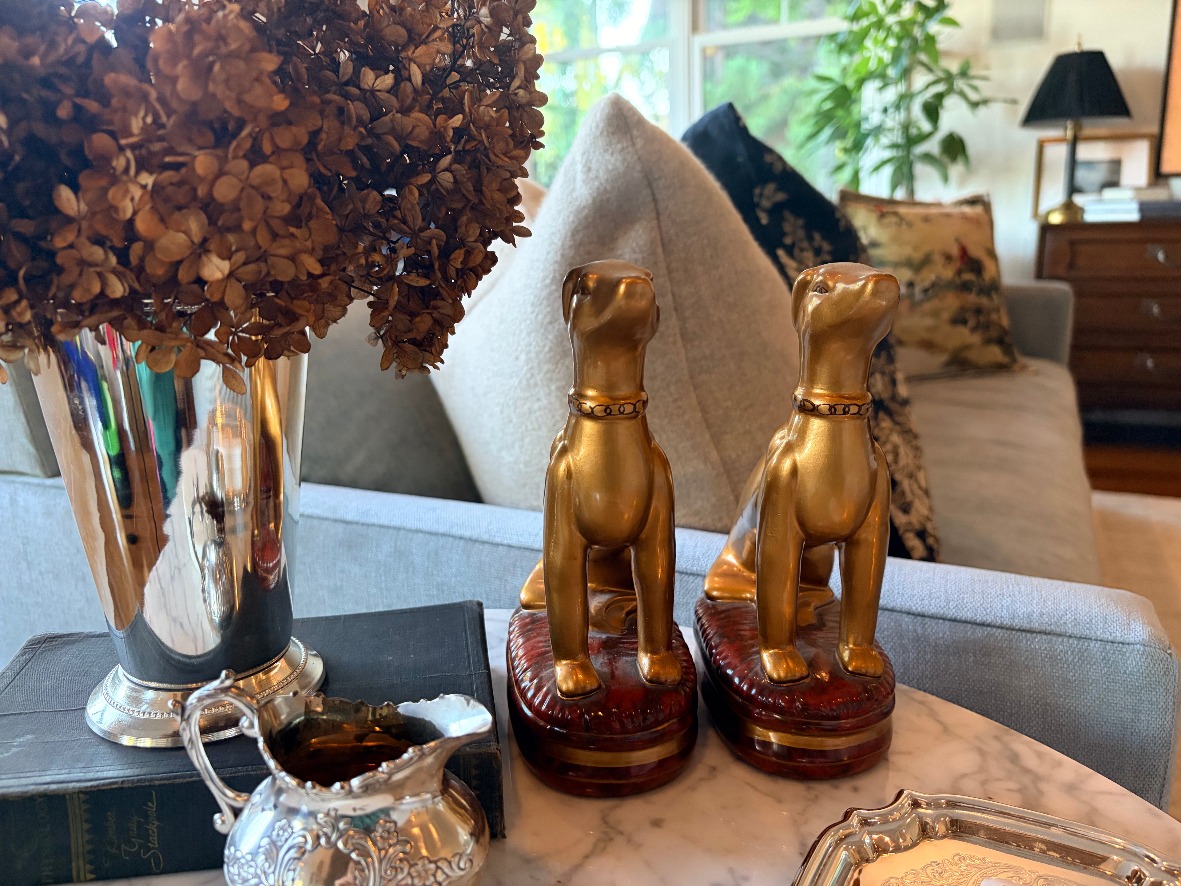 Pair of Raymond Waites gold whippet figurines styled on a bookshelf in a classic English library look